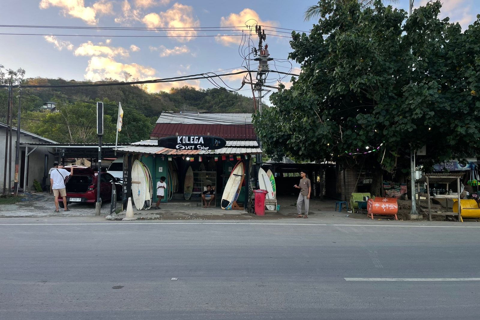 The front of Kolega Surf Shop on the main road in Kuta, boards lined up outside in the evening light